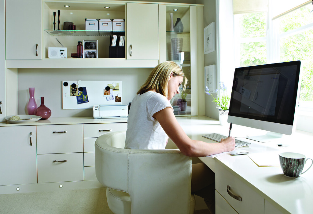 Woman working at a white desk in a sunny office.