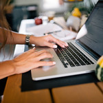 Closeup of a woman working diligently on a computer to complete her most recent assignment.