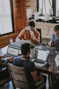 Group of people sitting around a table each working on a computer.